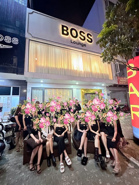 다낭 보스바 라운지 개업 축하 화환 앞에 앉은 직원들과 건물 간판