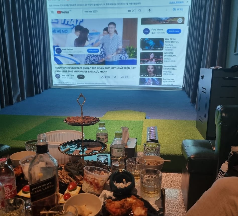 다낭 탑스크린 골프바 룸 — 스크린과 퍼팅 매트, 테이블에 차린 안주와 주류